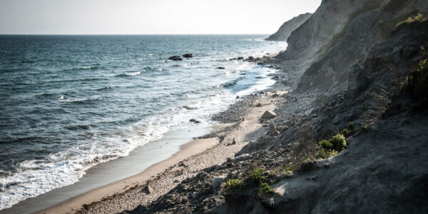 Scenic view of a rocky shoreline and waves crashing along the beach at the base of cliffs on Block Island